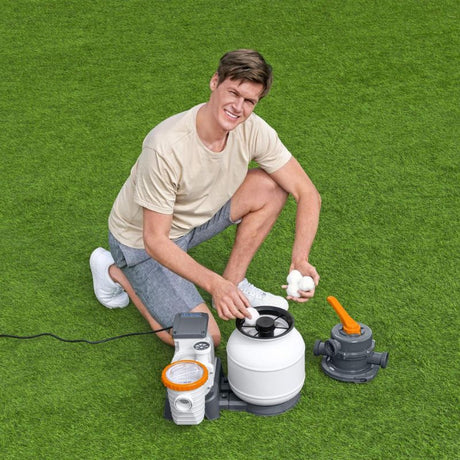 Uomo che carica le sfere Polysphere Bestway nella pompa filtro a sabbia per piscina fuori terra